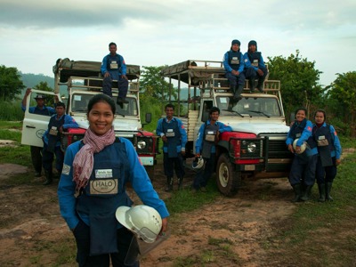 Deminers wearing protective gear pose with HALO vehicles 